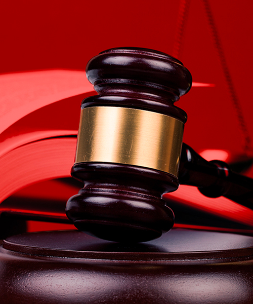 A judge's gavel rests on an open book, set against a vibrant red background, symbolizing law and justice.